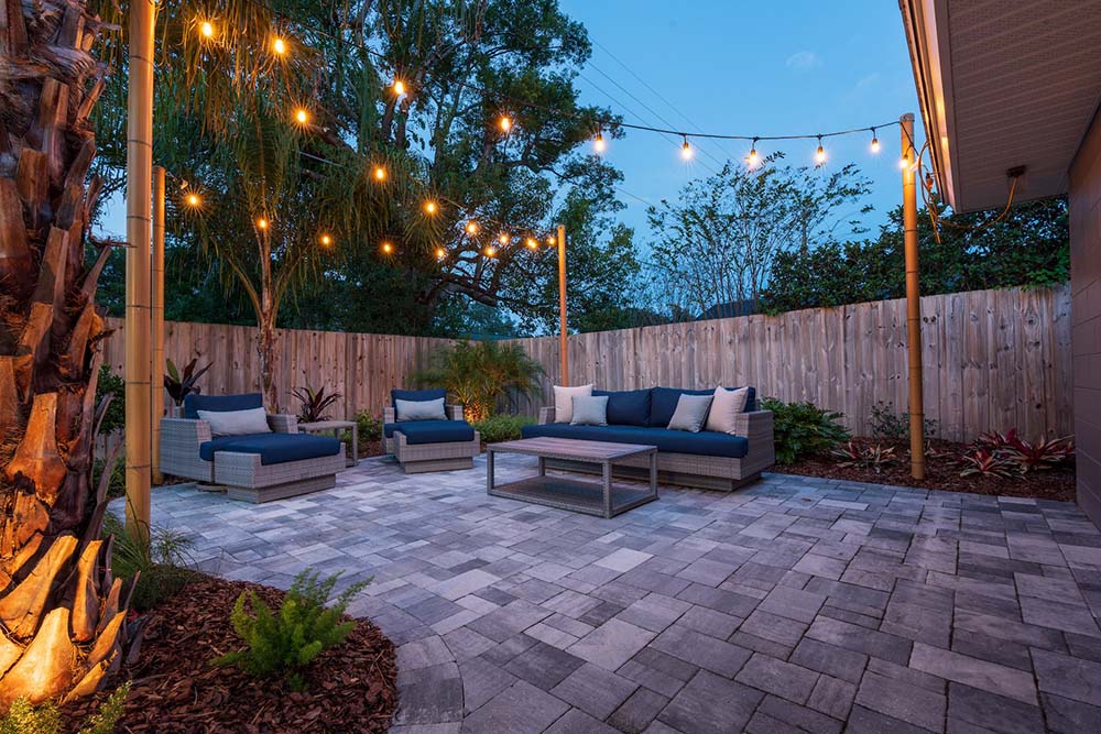 Paver patio in backyard with string lights