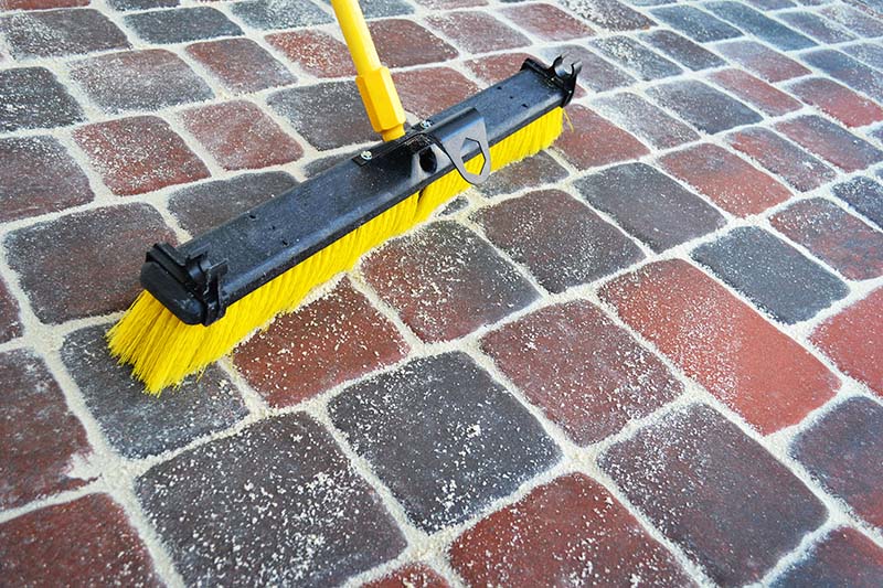 Person sweeping brick pavers